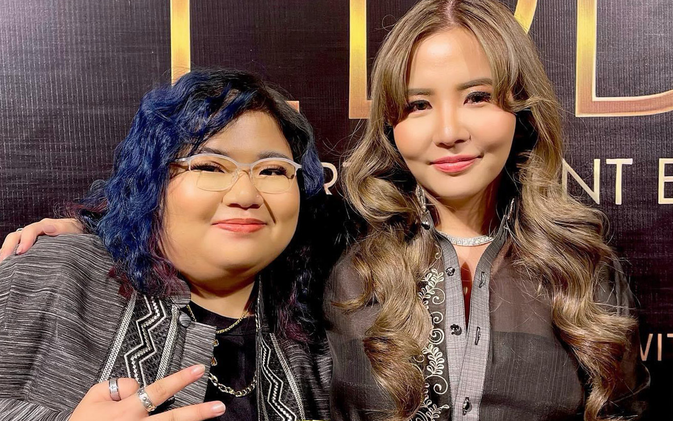 Ashley Aunor (left) and her sister Marion Aunor (right) in front of a black backdrop. 