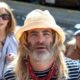 A long-haired, bearded Chris Pine with a hat in front of Annette Benning and Danny DeVito in Poolman