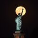 May's full Moon, known as the full flower moon, rises behind the Statue of Liberty on May 7, 2020, in New York City.