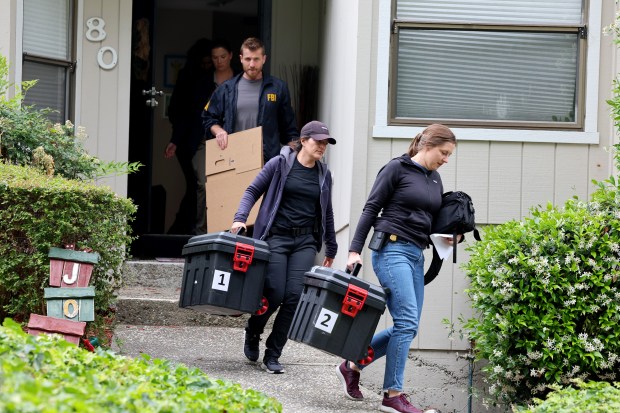 FBI agents carry boxes out of the house associated with...