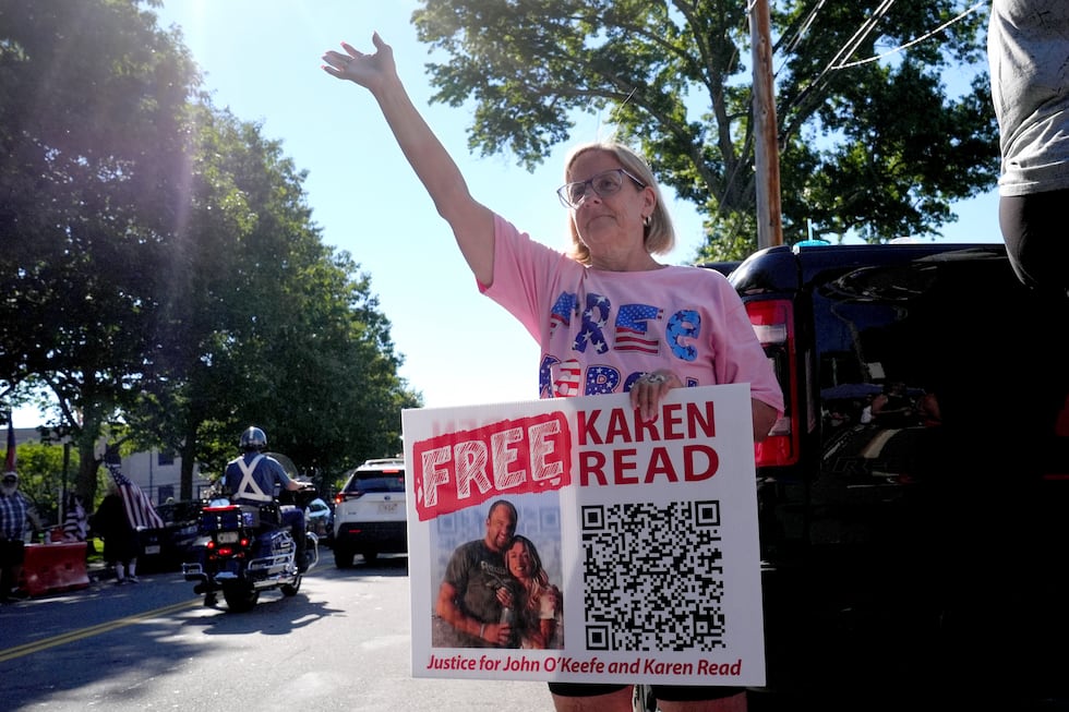 Laura McGillis, of Attleboro, Mass., a supporter of Karen Read, waves to passing cars a block...