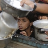 A Palestinian boy watches his portion of food aid ahead of the upcoming Eid al-Adha holiday in Jerusalem, Saturday, June 15, 2024. (AP Photo/Jehad Alshrafi)