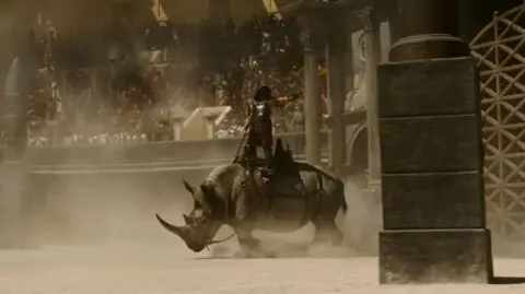 Paramount A rhino is ridden into action in the arena