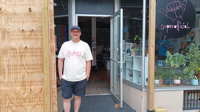 superofficial Owner Jon Matwijec-Walda stands outside his cafe and the plywood barrier put up after the storm blew out the large glass window.