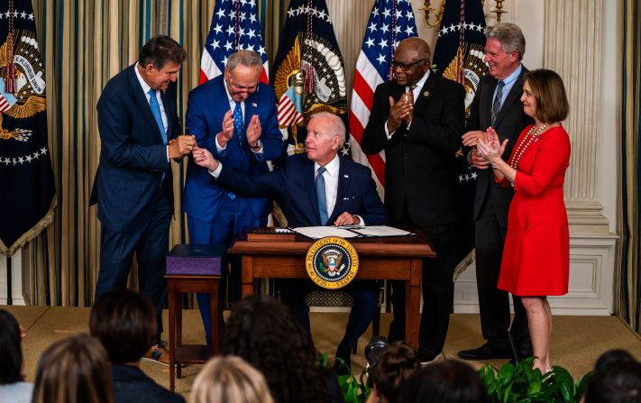 Biden hands West Virginia Sen. Joe Manchin the pen used to sign the Inflation Reduction Act at the White House in August 2022. Also pictured from left are Senate Majority Leader Chuck Schumer, House Majority Whip Rep. Jim Clyburn, New Jersey Rep. Frank Pallone and Florida Rep. Kathy Castor. 