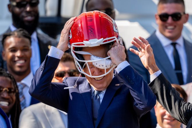 Biden puts on a Kansas City Chiefs football helmet as he welcomes the Super Bowl champions to the White House in May 2024.