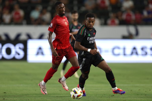 Arsenal defender Jurrien Timber, front, moves the ball against AFC...