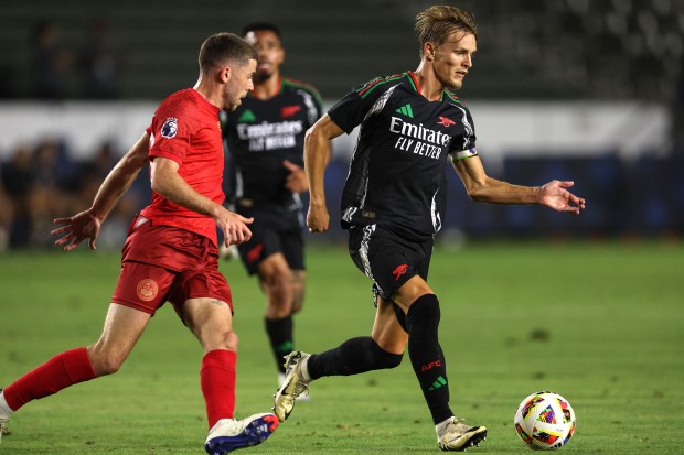 Arsenal midfielder Martin Ødegaard, right, kicks the ball past AFC...