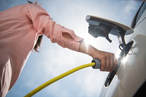 A person plugging in an EV to recharge the battery.