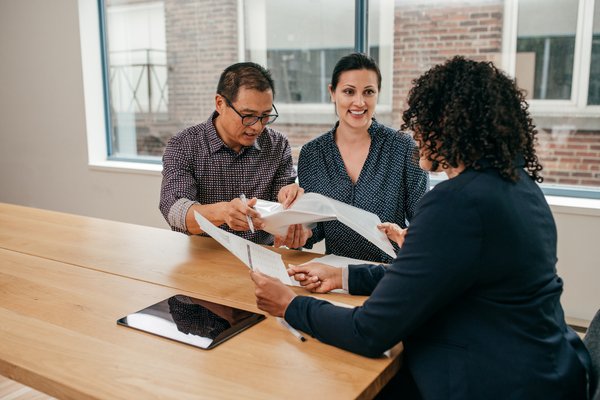 Three people sitting at table reviewing documents.