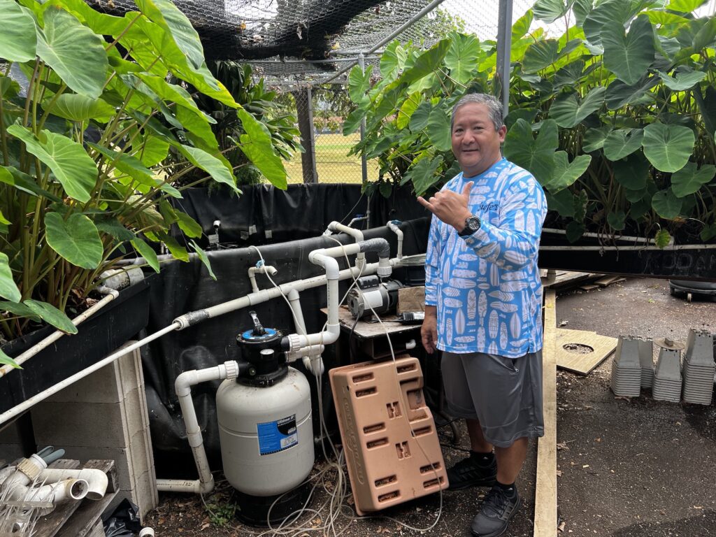 Principal Garret Zakahi in front of one of his aquaponics systems. (Catherine Toth Fox/Civil Beat/2024)