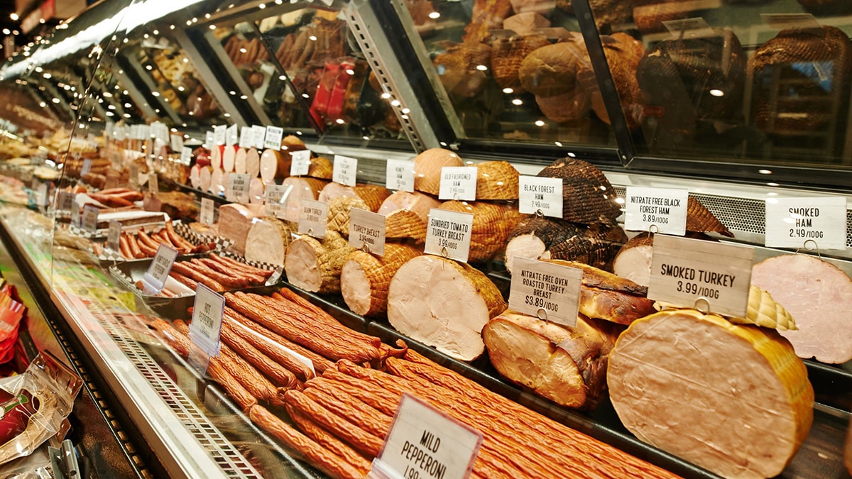 Rows of sliced deli meats in a grocery store setting.