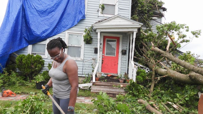 Rome resident Sharon Samuels rakes debris from trees toppled near her home on West Embargo Street.