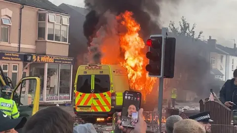 PA Media A police van on fire in Southport