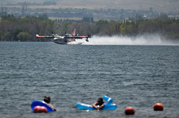 As beachgoers relax in the water an air tanker skims the waters of Chatfield Reservoir while refilling for the aerial fire fight against the Quarry fire in Jefferson County just west of Chatfield Reservoir on Wednsday, July 31, 2024. (Photo by Eric Lutzens/The Denver Post)