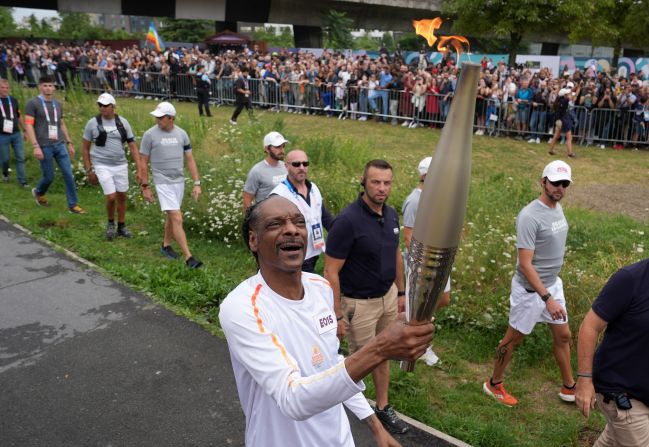 Rapper Snoop Dogg carries the Olympic torch during the torch relay on July 26.