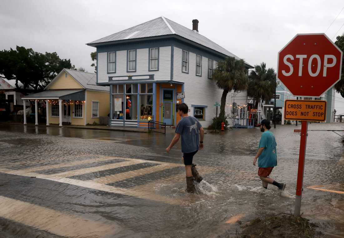 People walk through a flooded street caused by the rain and storm surge from Hurricane Debby in Cedar Key, Florida, on Monday, August 5.