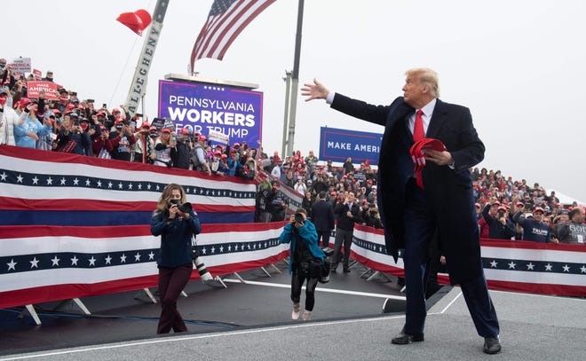 US President Donald Trump throws MAGA hats to the crowd as he holds a Make America Great Again campaign rally at Lancaster Airport in Lititz, Pennsylvania, October 26, 2020.