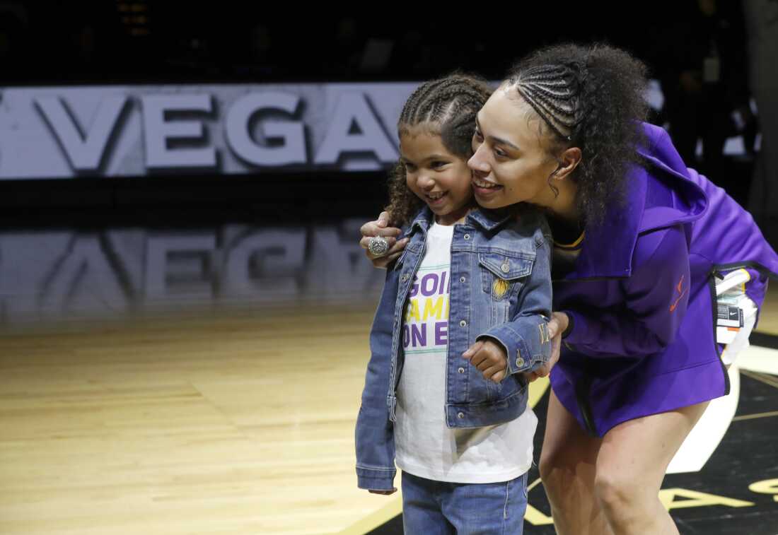 Dearica Hamby poses with her daughter Amaya on a basketball court, both wearing purple.