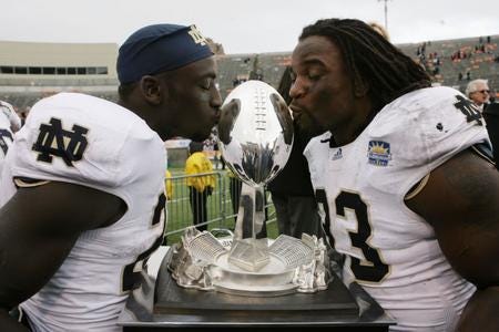 Notre Dame teammates Cierre Wood and Robert Hughes plant a kiss on the 77th Annual Hyundai SUn Bowl trophy after defeating the University of Miami Hurricanes 33-17.