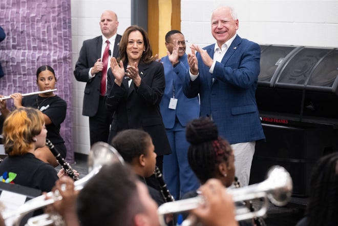 Democratic presidential running mates Kamala Harris and Tim Walz applaud a marching band at Liberty County High School in Hinesville, Ga., on Aug. 28, 2024, while on a campaign bus tour.