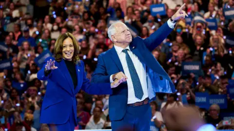 Getty Images US Vice-President Kamala Harris and  her running mate Tim Walz stand on stage during a campaign event  in Milwaukee, Wisconsin on 20 August, 2024