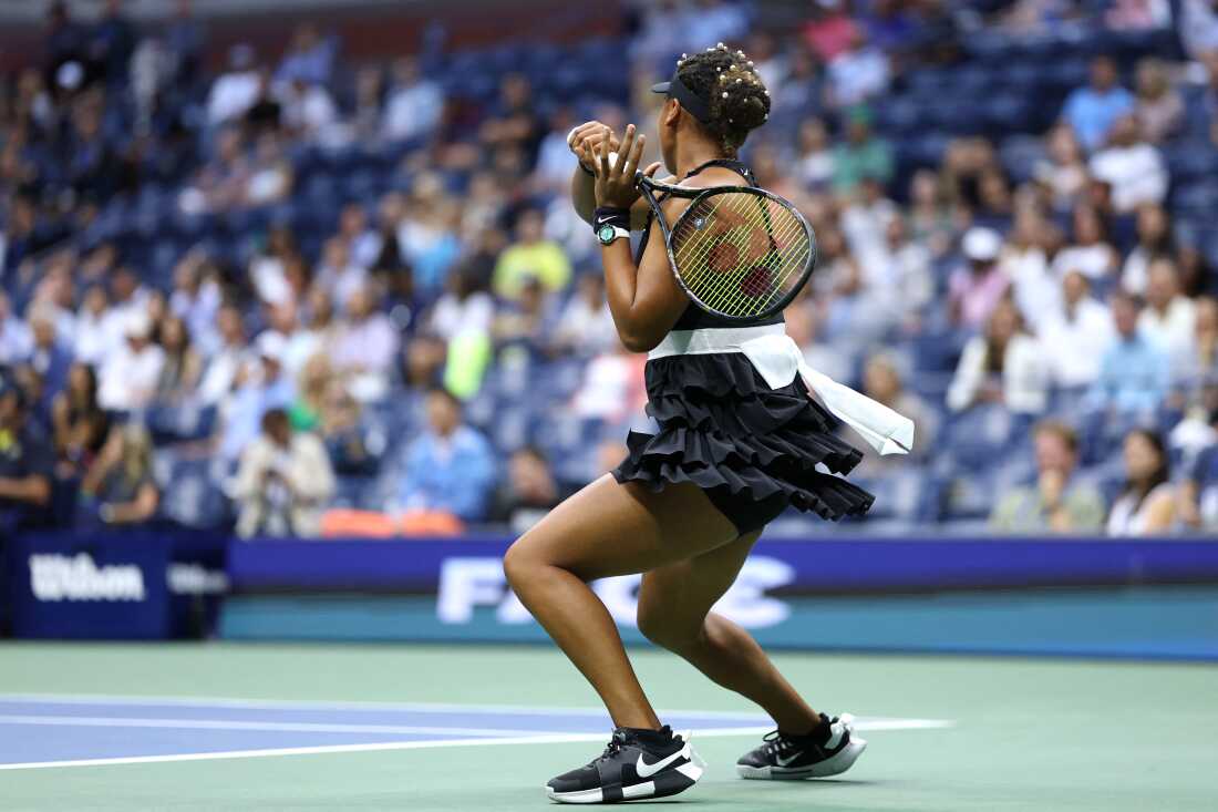 Naomi Osaka hits the ball in front of a crowd. 