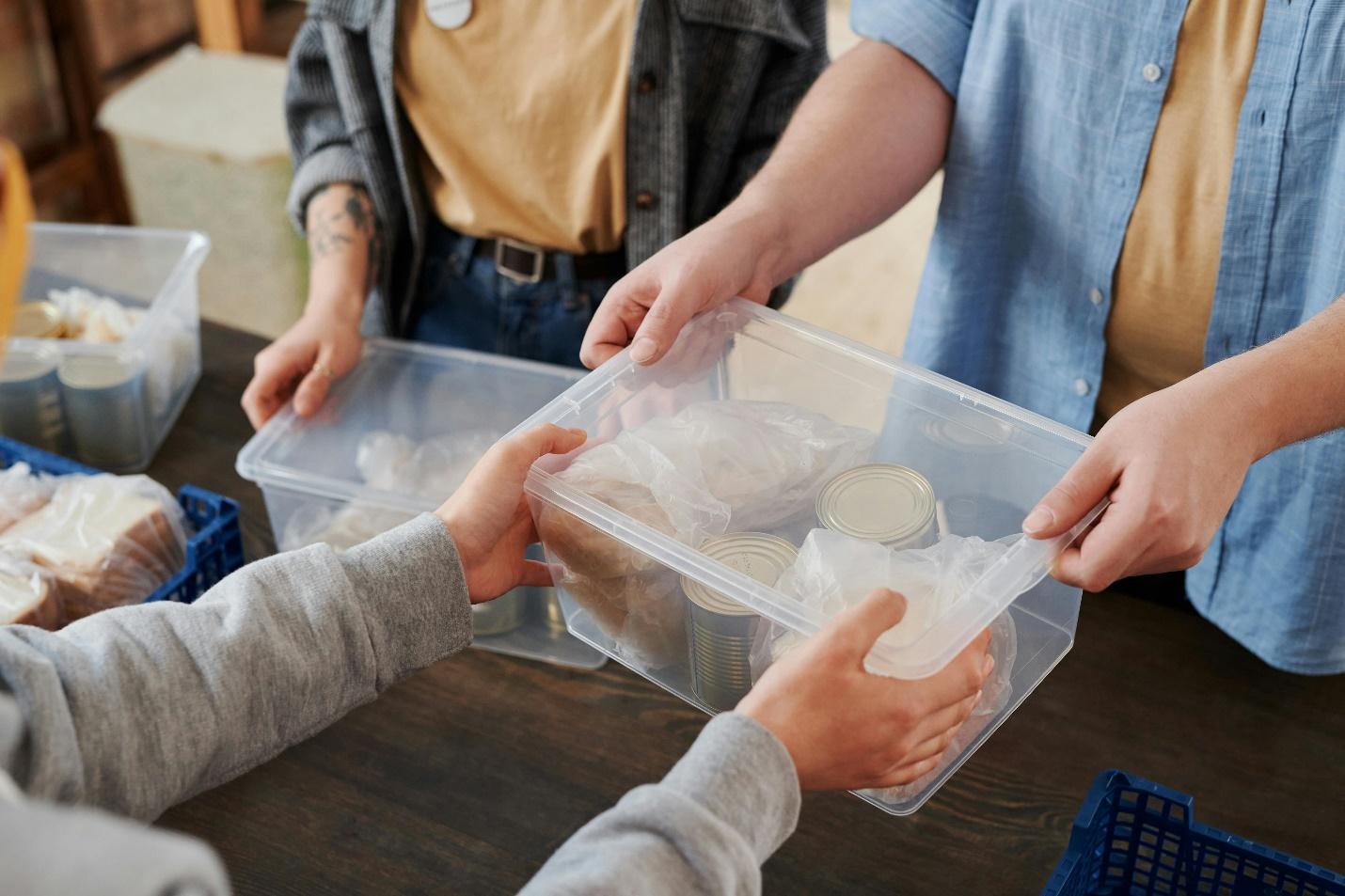 A group of people holding a plastic container of food

Description automatically generated