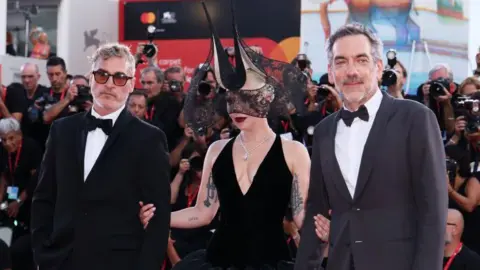 Getty Images Joaquin Phoenix, Lady Gaga and director Todd Phillips at the Venice premiere with crowds of photographers on the red carpet