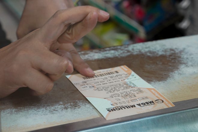 A hopeful player fills crosses her fingers as she buys a Mega Millions ticket.