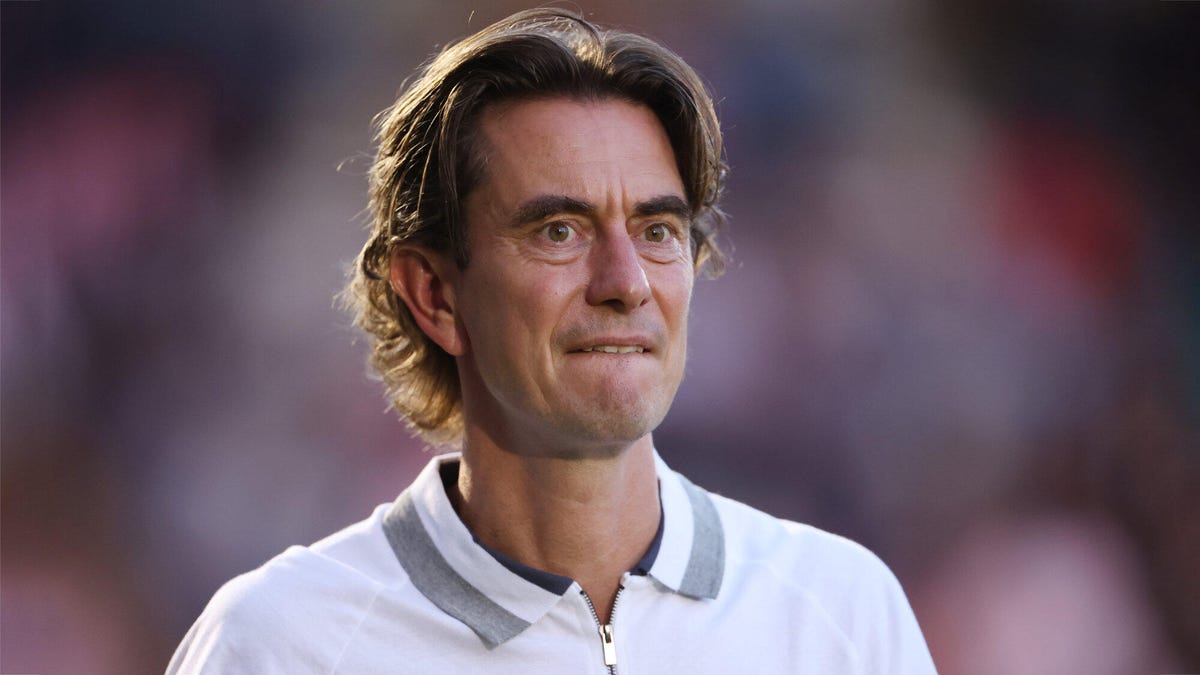 Brentford manager Thomas Frank looking onwards, wearing a white polo shirt.