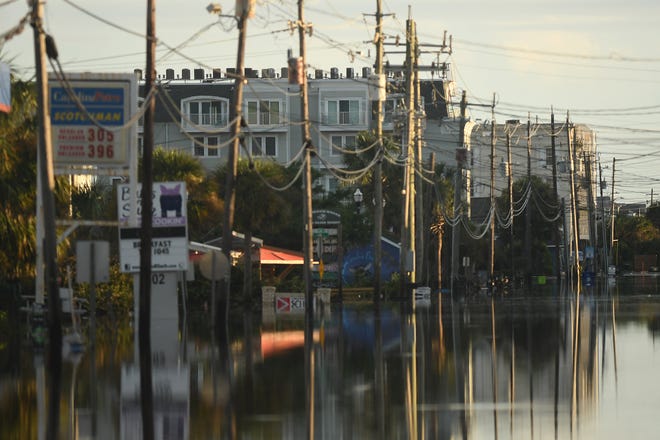 Residents and others look over the standing floodwaters that remain around the Carolina Beach Lake area Tuesday, Sept. 17, 2024 in Carolina Beach, N.C.