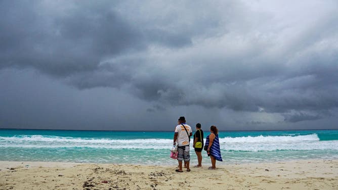 Storm clouds are pictured as people walk on the beach ahead of the arrival of Hurricane Helene in Cancun, Quintana Roo state, Mexico on September 24, 2024.