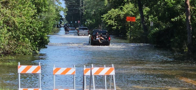 A tow truck hauled flooded vehicles out of 115th Street near the Cortez Road intersection late Friday morning, just before other residents drove into the same floodwaters to reach their homes on a day of Hurricane Helene recovery efforts.