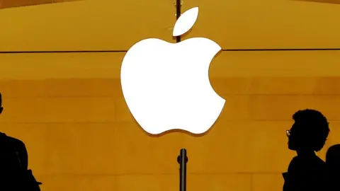 Reuters Apple logo glows in white on yellow background with shadows of people walking past