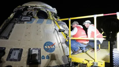 NASA Boeing and NASA teams work around the Starliner spacecraft after it landed on Saturday