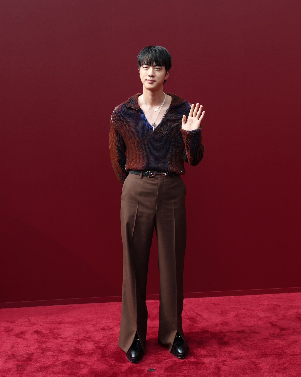 Jin in front of a red backdrop.