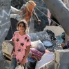 A girl wearing blue jeans and a pink shirt with black stars walks through the rubble of a collapsed building in Khan Younis, in the southern Gaza Strip, on October 2, 2024. Chunks of concrete surround her, along with items from destroyed homes, such as a wall clock.