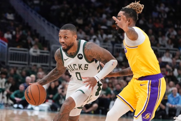 Milwaukee Bucks star Damian Lillard tries to drive past Lakers...