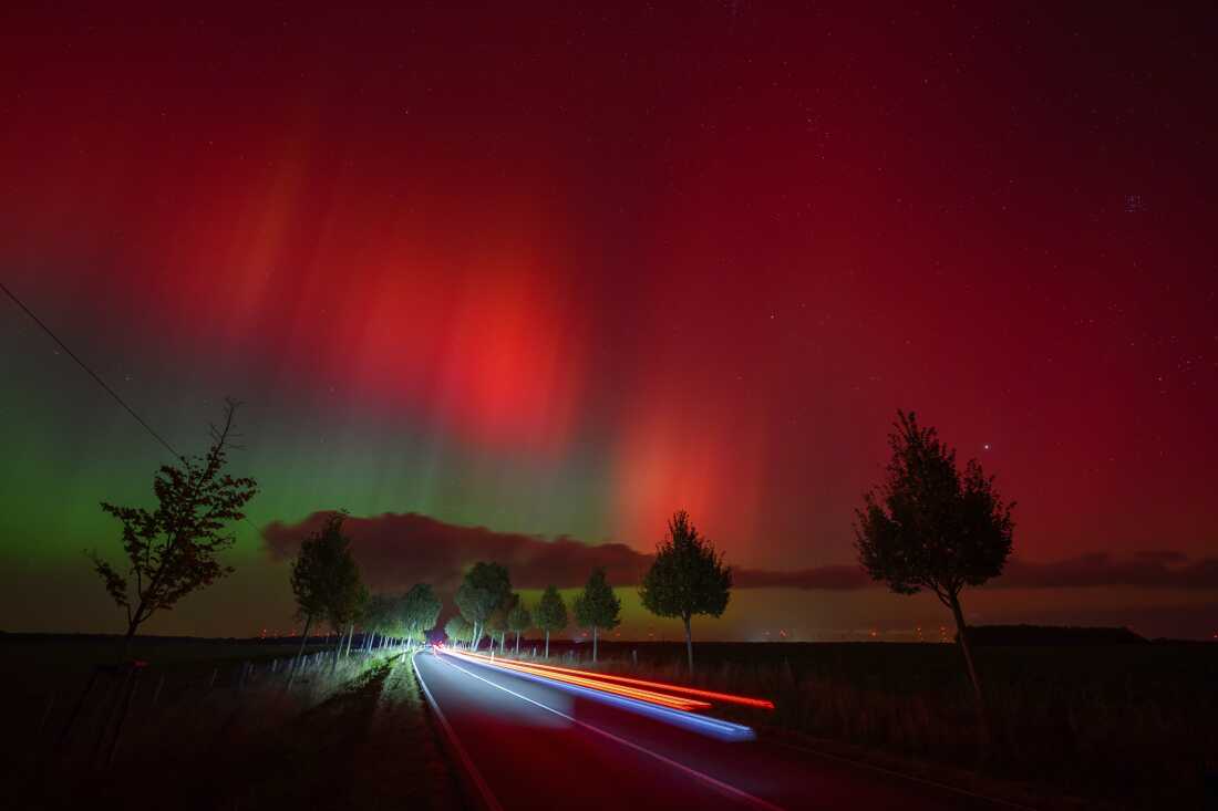 Northern lights glow in the night sky above a road in eastern Brandenburg, Germany.