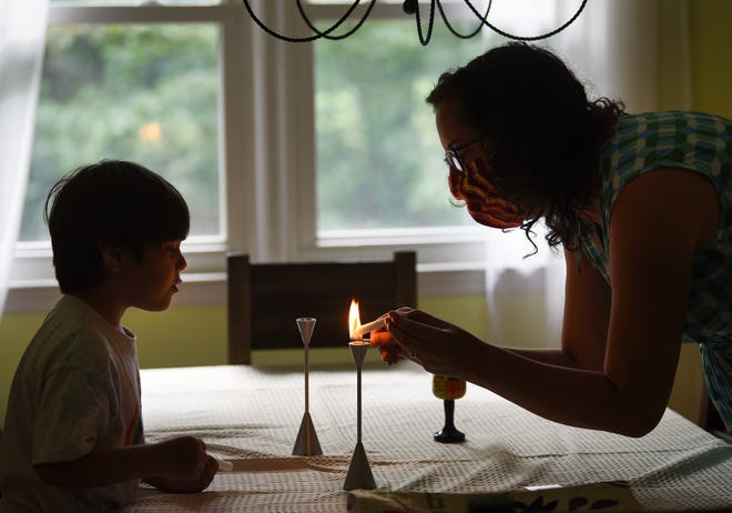 Rabbi Rebecca Gutterman of Temple Emanu-El, who is accustomed to leading the services for her congregation of hundreds of people, melts part of the candle on the top of the candle holder as her son Jonah (4) looks on,  for Yom Kippur at the Rabbi's house in Metuchen on September 27,2020.