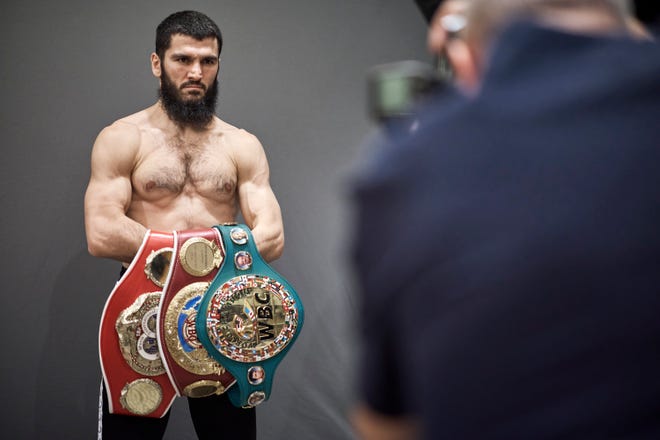 Artur Beterbiev poses with his IBF, WBO and WBC light heavyweight titles ahead of his undisputed title fight against WBA champion Dmitry Bivol on Oct. 12.