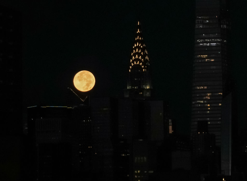 A orange sphere next to a dark barely illuminated spire