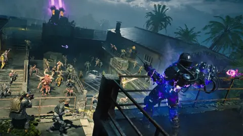 Microsoft Activision Blizzard A screengrab from the game, of several characters battling zombie-like figures in the game, with one character at a higher vantage point on a roof, as several others fight below. There are palm trees in the distance with pink lasers being shot into the sky.