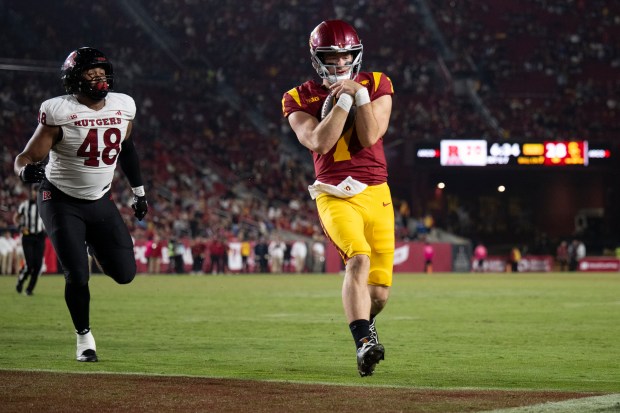 USC quarterback Miller Moss, right, runs with the ball to...