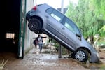 TOPSHOT - A resident walks next to a car lifted up in a street covered in mud in a flooded area in Picanya, near Valencia, eastern Spain, on October 30, 2024. Floods triggered by torrential rains in Spain's eastern Valencia region has left 51 people dead, rescue services said on October 30. (Photo by Jose Jordan / AFP) (Photo by JOSE JORDAN/AFP via Getty Images)