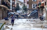 TOPSHOT - Residents are pictured next to cars piled in a street covered in mud following floods in Picanya, near Valencia, eastern Spain, on October 30, 2024. Floods triggered by torrential rains in Spain's eastern Valencia region has left 51 people dead, rescue services said on October 30. (Photo by Jose Jordan / AFP) (Photo by JOSE JORDAN/AFP via Getty Images)