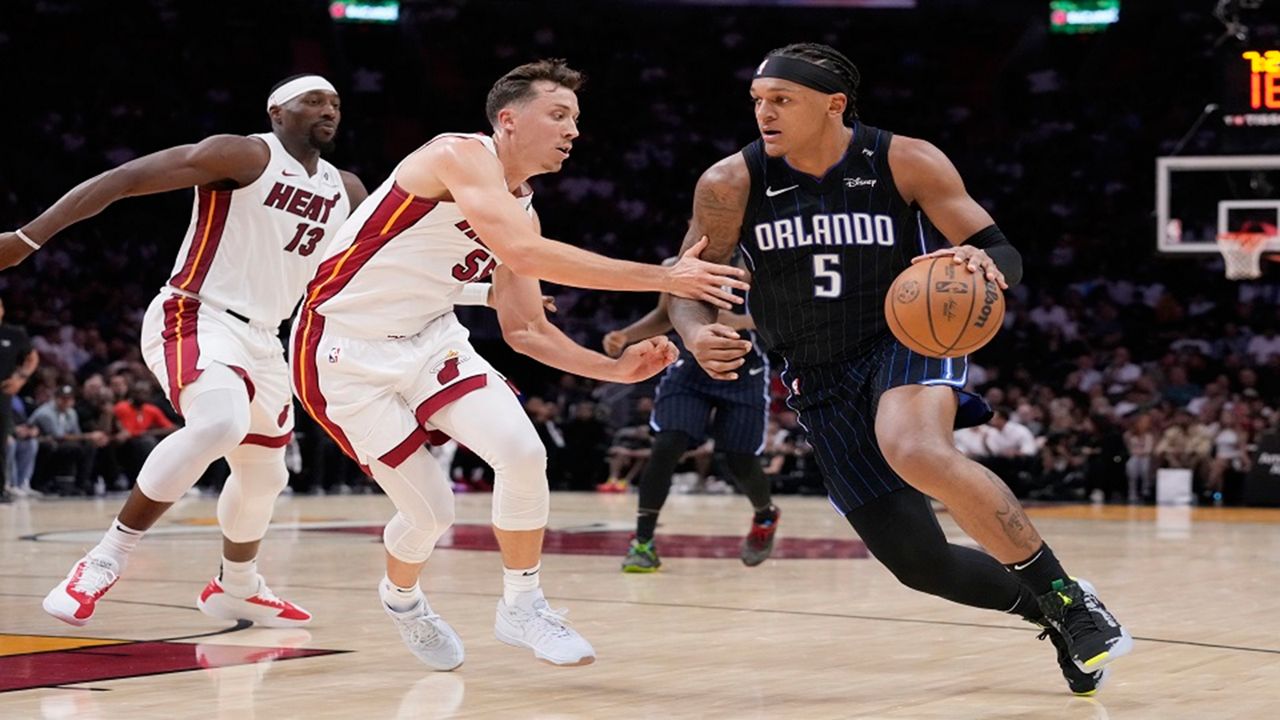 Orlando Magic forward Paolo Banchero (5) drives to the basket against Miami Heat forward Duncan Robinson (55) and center Bam Adebayo (13) during the first half of an NBA basketball game, Wednesday, Oct. 23, 2024, in Miami. (AP Photo/Wilfredo Lee)