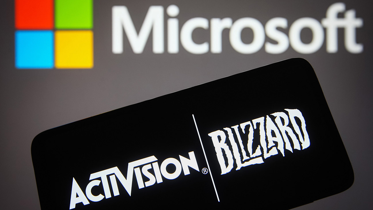 In this photo illustration, the Activision Blizzard logo is seen displayed on a smartphone screen with the Microsoft Corporation logo in the background.