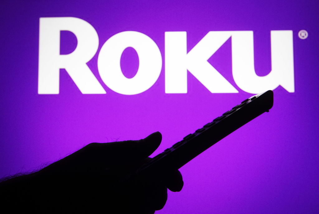 UKRAINE - 2021/07/04: In this photo illustration a Roku logo is seen on a screen with a silhouette of a hand holding a tv remote. (Photo Illustration by Pavlo Gonchar/SOPA Images/LightRocket via Getty Images)